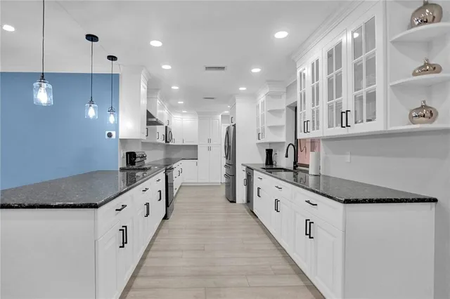a large kitchen with stainless steel appliances lots of counter space wooden floor and a sink