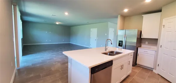 a kitchen that has a sink a refrigerator and a stove top oven