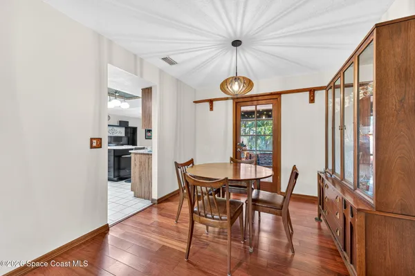 a dining room with furniture a chandelier and wooden floor
