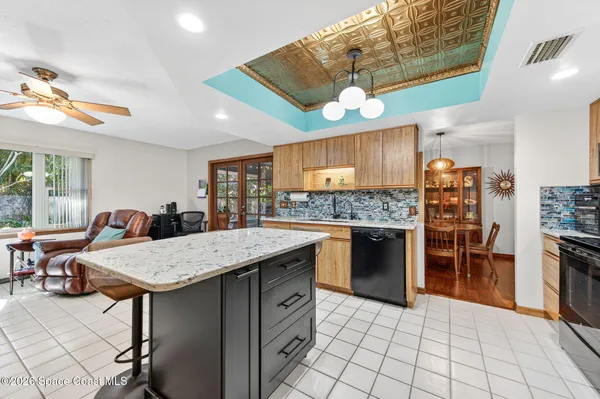 a kitchen with stainless steel appliances granite countertop a stove a refrigerator a sink a dining table and chairs with wooden floor