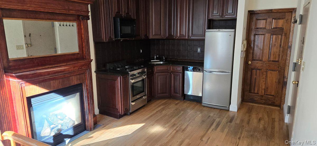 235 West 137th Street, Unit 1F Manhattan, NY 10030 - Photo 2 of 27 a kitchen with a refrigerator a stove top oven and wooden floor