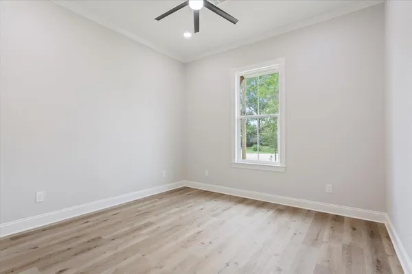 an empty room with wooden floor ceiling fan and window