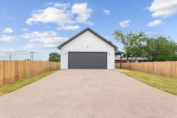a view of backyard of house with wooden fence