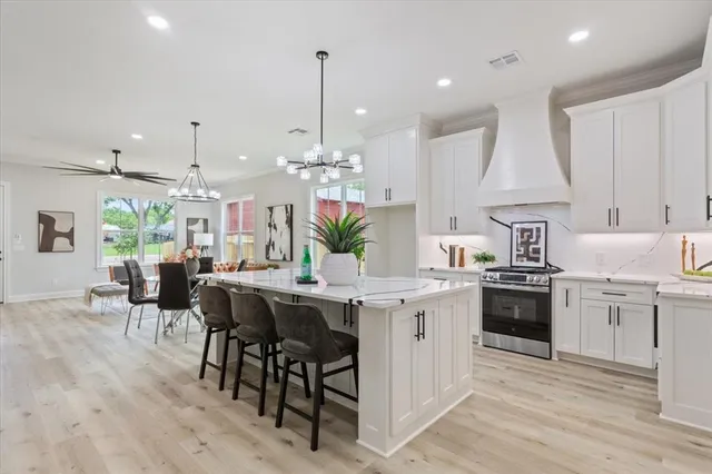 a kitchen with stainless steel appliances kitchen island granite countertop a table chairs sink and cabinets