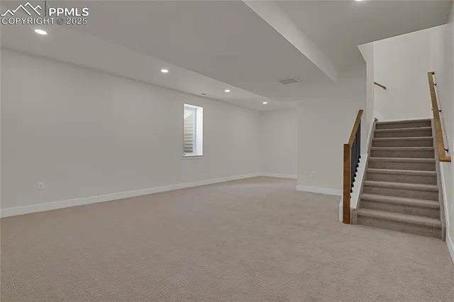 a view of an empty room with wooden floor and windows