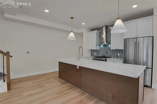 a large kitchen with a sink stainless steel appliances and wooden floor