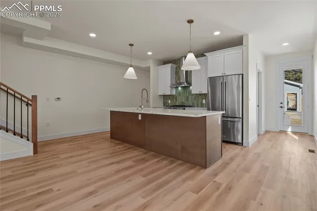 a kitchen with stainless steel appliances kitchen island granite countertop a refrigerator and a sink