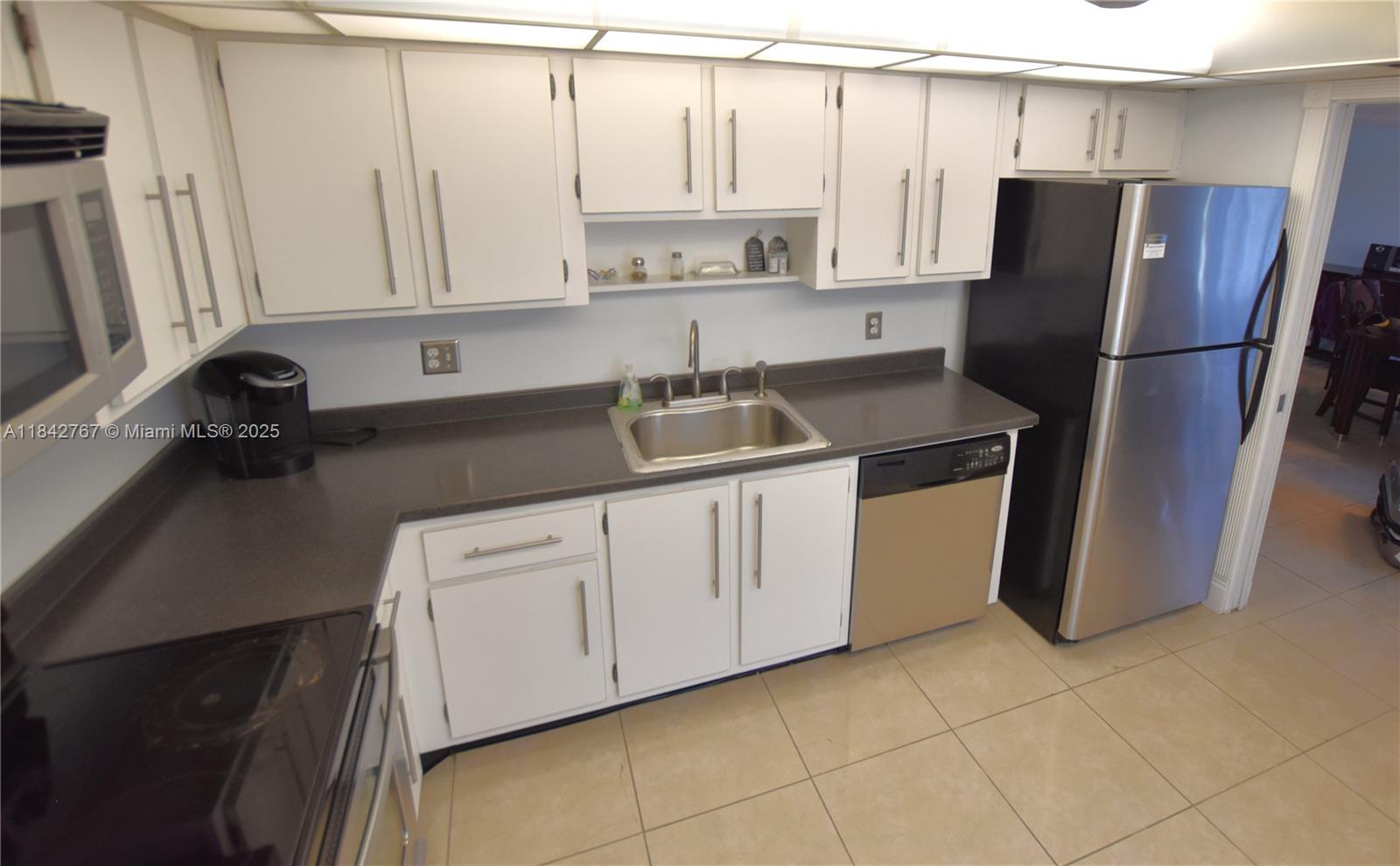3800 Oaks Clubhouse Drive, Unit 309 Pompano Beach, FL 33069 - Photo 19 of 47 a kitchen with a refrigerator sink and cabinets