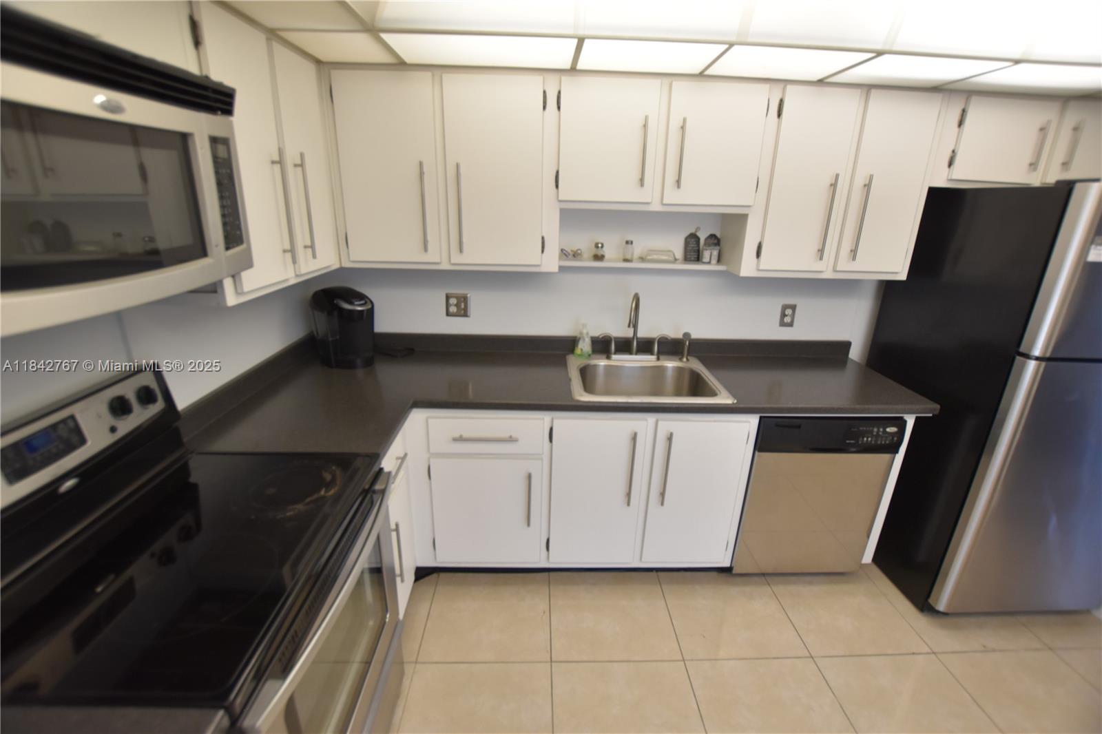 3800 Oaks Clubhouse Drive, Unit 309 Pompano Beach, FL 33069 - Photo 20 of 47 a kitchen with stainless steel appliances a refrigerator sink and microwave