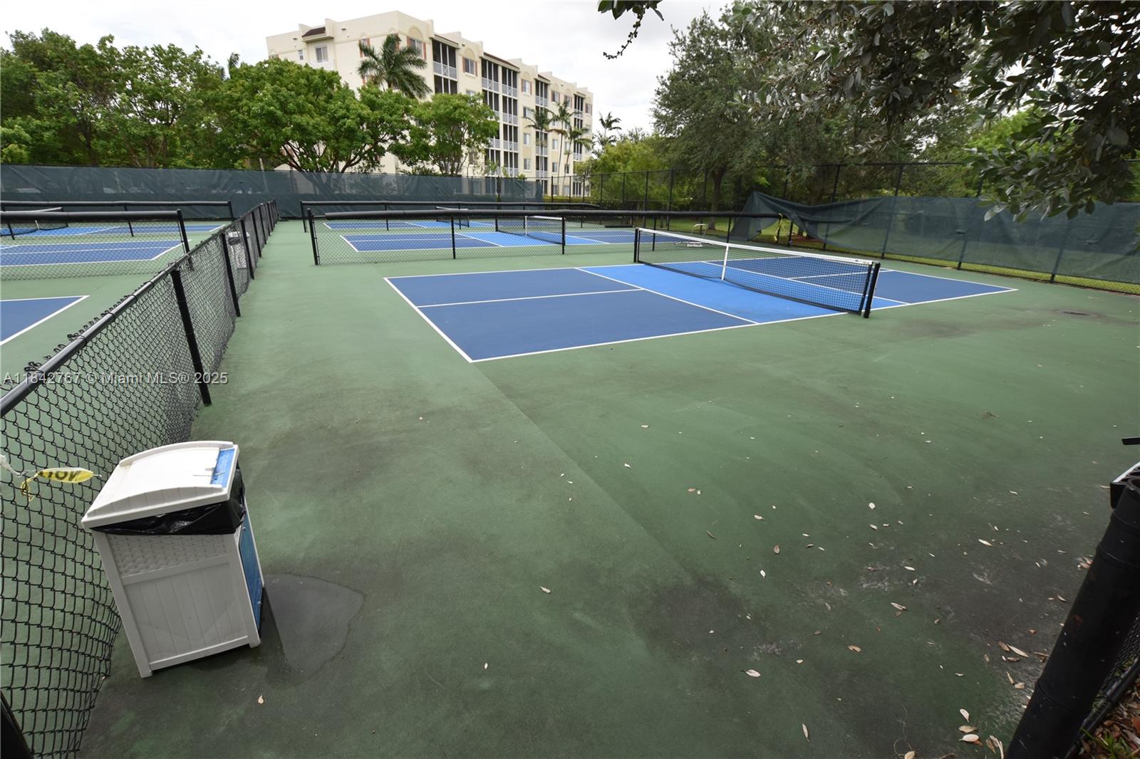 3800 Oaks Clubhouse Drive, Unit 309 Pompano Beach, FL 33069 - Photo 40 of 47 a view of a tennis ground with large trees