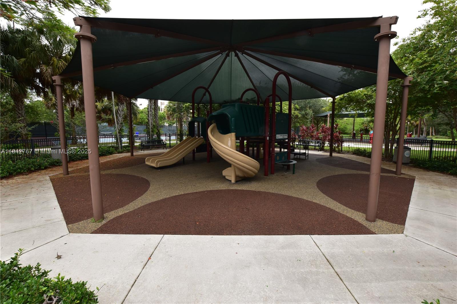 3800 Oaks Clubhouse Drive, Unit 309 Pompano Beach, FL 33069 - Photo 45 of 47 a view of a patio with a table and chairs under an umbrella