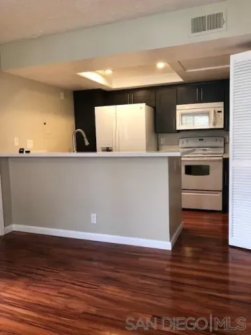 a view of kitchen with stainless steel appliances wooden floor and cabinets