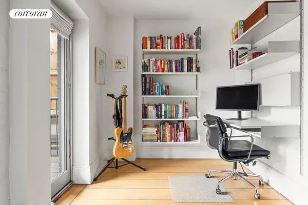 a view of a workspace with furniture and a book shelf