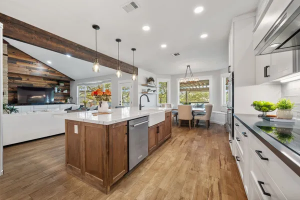 a large white kitchen with stainless steel appliances kitchen island granite countertop a large counter top and white cabinets