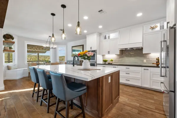 a kitchen with stainless steel appliances kitchen island granite countertop a table chairs and a refrigerator