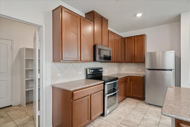 a kitchen with stainless steel appliances granite countertop a refrigerator and a stove top oven