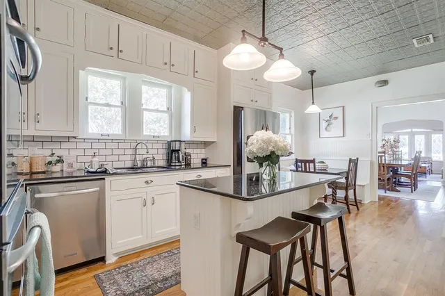 a kitchen with stainless steel appliances granite countertop a stove a sink dishwasher a dining table and chairs with wooden floor