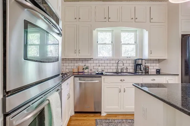 a kitchen with stainless steel appliances white cabinets and a window