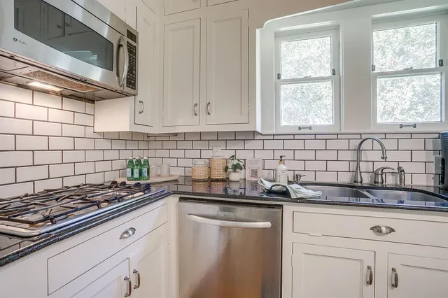 a kitchen with granite countertop white cabinets stainless steel appliances and sink