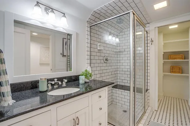 a bathroom with a granite countertop sink a mirror and shower