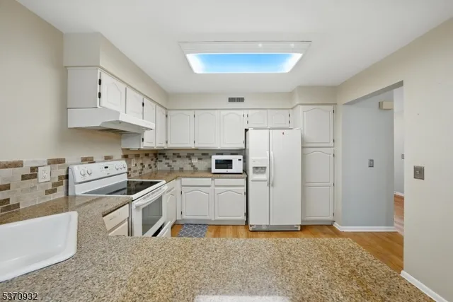 a kitchen with stainless steel appliances granite countertop a refrigerator a stove and white cabinets