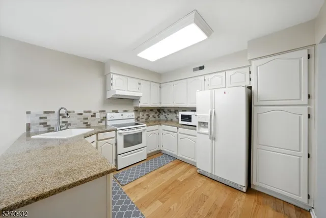 a kitchen with white cabinets and white appliances
