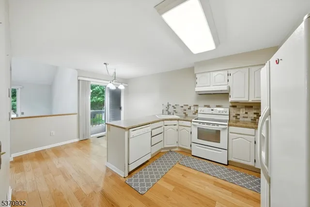 a kitchen with white cabinets appliances and a window