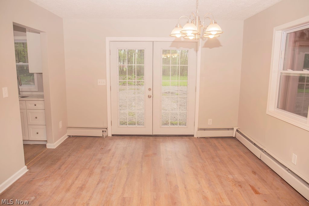 3644 Padanarum Road Geneva, OH 44041 - Photo 3 of 19 Spacious room featuring wood-finish flooring, neutral-toned walls, and a multi-light chandelier