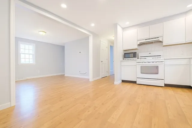 a kitchen with granite countertop white cabinets and white appliances