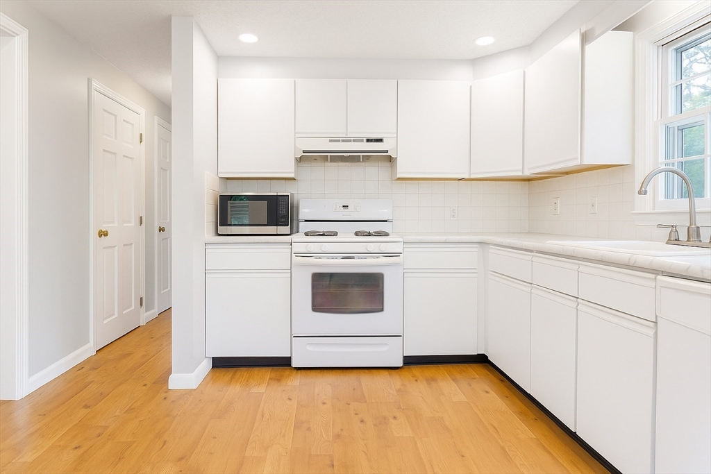 49 St Marks Road Falmouth, MA 02536 - Photo 18 of 38 a kitchen with granite countertop white cabinets and white appliances