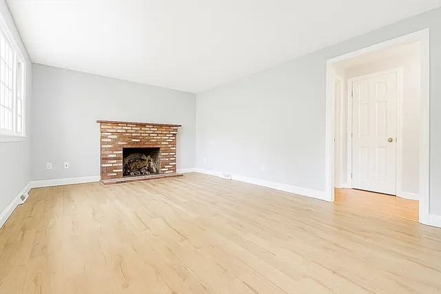 an empty room with windows and fireplace