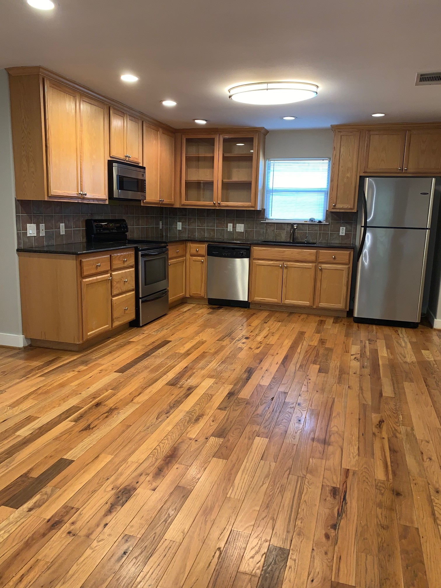 a large kitchen with stainless steel appliances granite countertop a stove a sink and a refrigerator