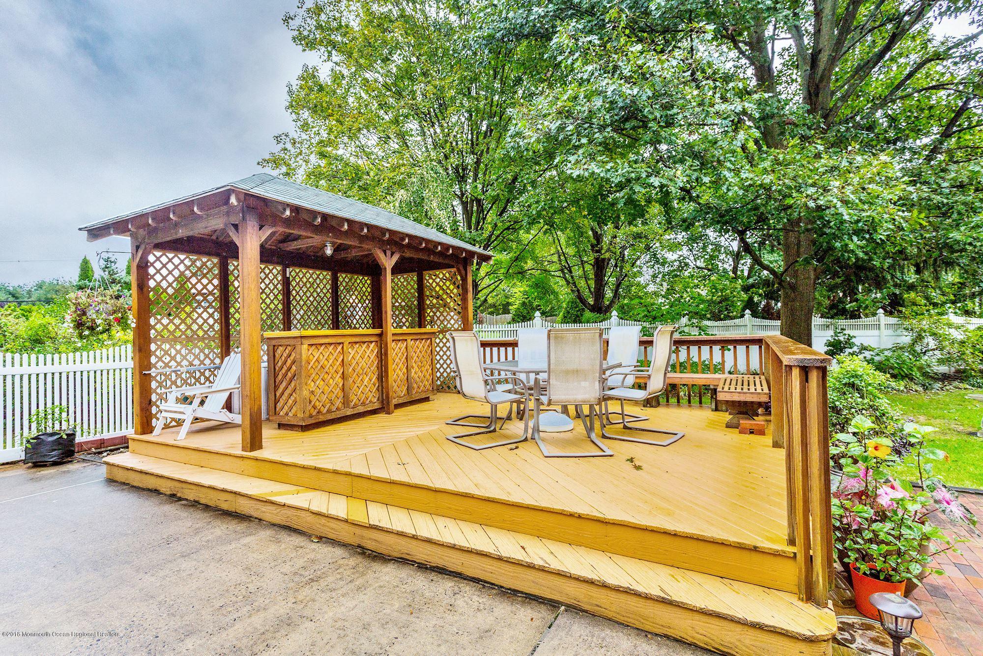 3 East Point Road Lincroft, NJ 07738 - Photo 37 of 42 a view of a patio with a table and chairs under an umbrella with wooden fence