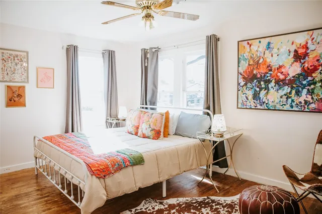 a bedroom with a bed a painting on the wall and a large window