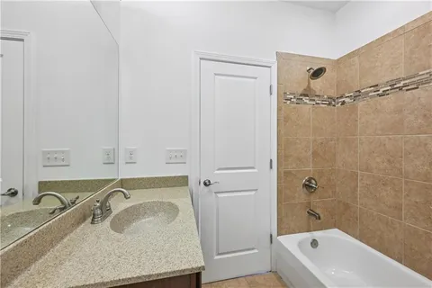 a bathroom with a granite countertop tub sink and mirror