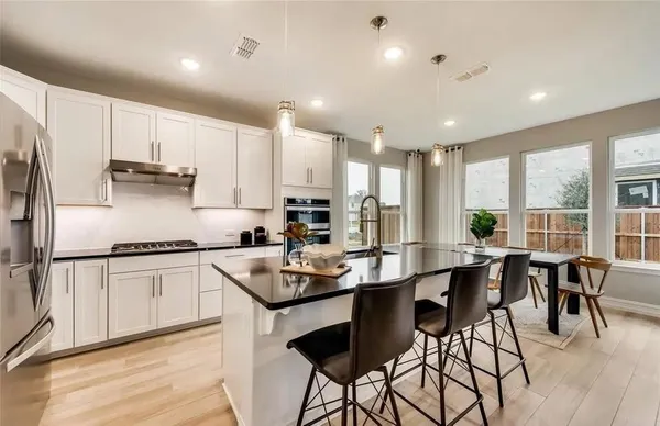 a kitchen with stainless steel appliances granite countertop a stove refrigerator sink cabinets dining table and chairs