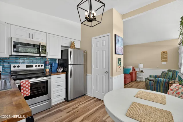 a kitchen with stainless steel appliances granite countertop a dining table chairs and a sink