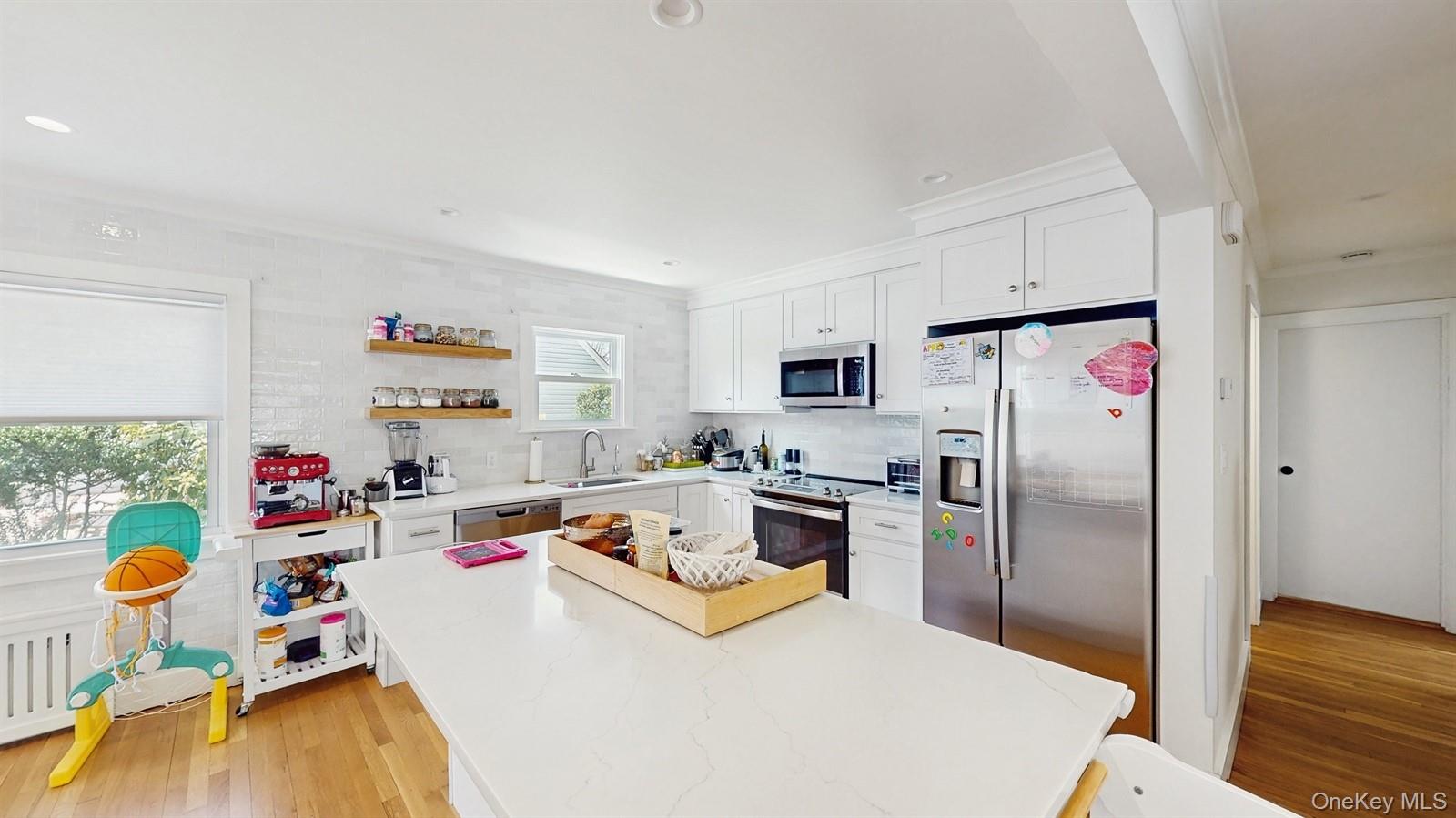 170 Wetherill Road Garden City, NY 11530 - Photo 11 of 23 Kitchen featuring light wood-style flooring, white cabinetry, a kitchen island, a sink, and stainless steel appliances