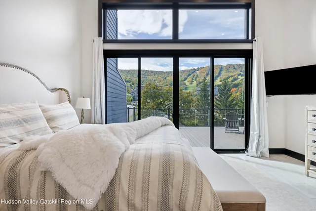 a bedroom with a bed lamp and a large window