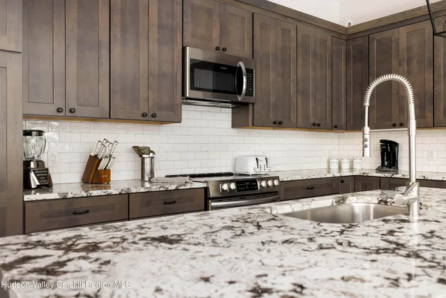 a kitchen with kitchen island granite countertop a sink cabinets a refrigerator and a stove