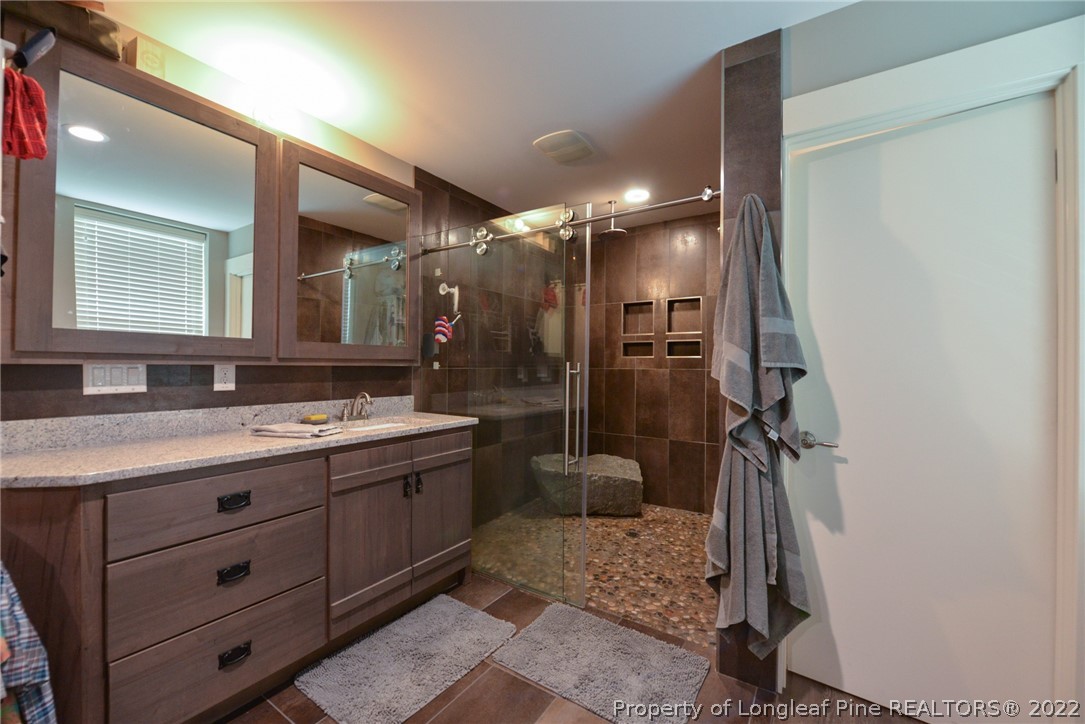 5671 Stewart Road Godwin, NC 28344 - Photo 20 of 45 a bathroom with a double vanity sink a toilet a mirror and shower