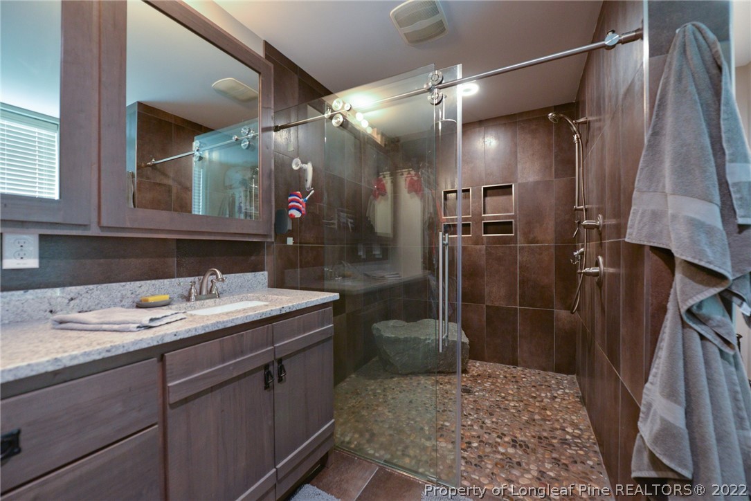 5671 Stewart Road Godwin, NC 28344 - Photo 21 of 45 a bathroom with a sink vanity granite shower and a mirror