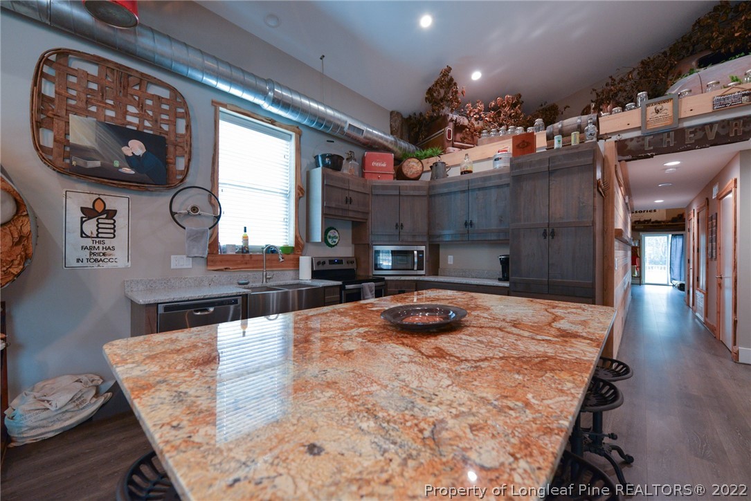 5671 Stewart Road Godwin, NC 28344 - Photo 7 of 45 a kitchen with stainless steel appliances granite countertop a sink and a wooden cabinets