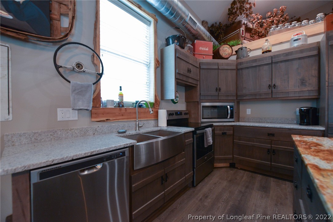 5671 Stewart Road Godwin, NC 28344 - Photo 8 of 45 a kitchen with stainless steel appliances granite countertop a sink a stove and a microwave oven with cabinets