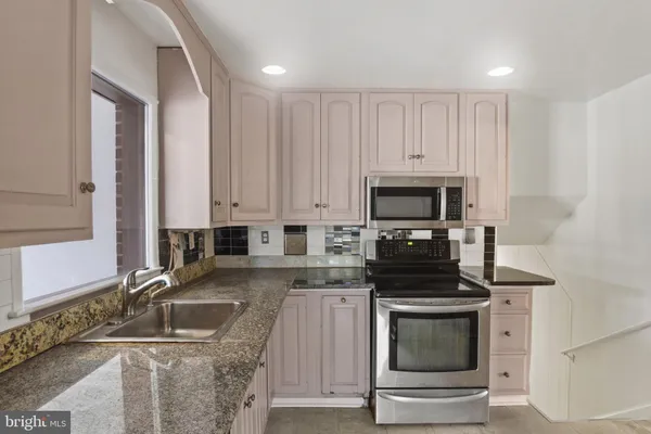 a kitchen with granite countertop a stove sink and microwave