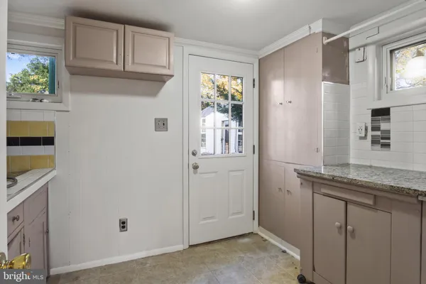 a kitchen with stainless steel appliances granite countertop white cabinets and a window