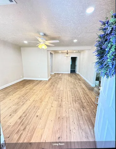 a view of a room with wooden floor ceiling fan and window