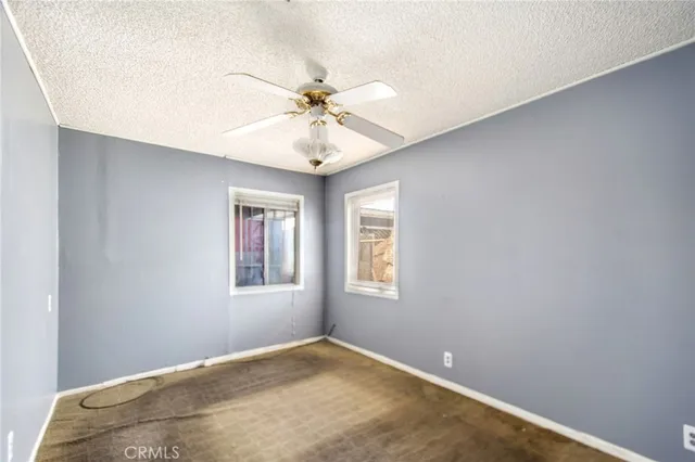 an empty room with windows and fan