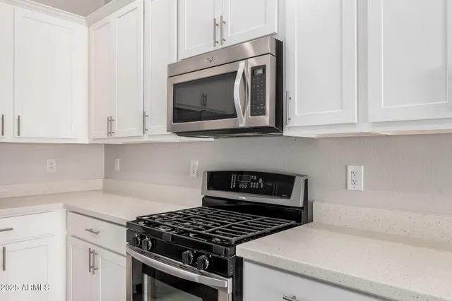 a kitchen with stainless steel appliances granite countertop white cabinets and a stove top oven