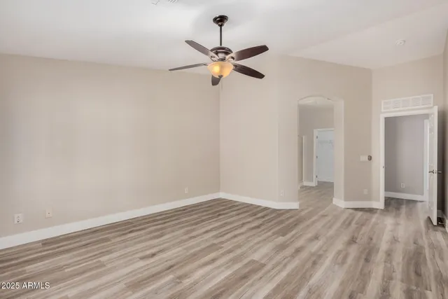 a view of empty room with wooden floor and ceiling fan